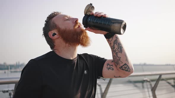 Bearded Athlete Drinks Water From Thermos After Training