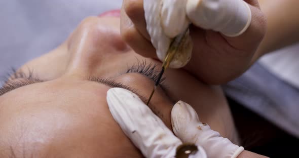 Young woman gets facial beauty procedure, microblading procedure on woman eye at beauty salon