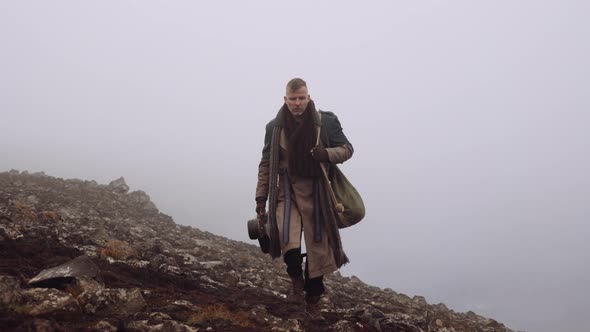 Man In Greatcoat Walking Through Misty And Rocky Landscape