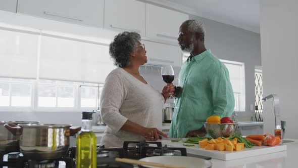 A senior african american couple spending time together at home enjoying a glass of wine social dist