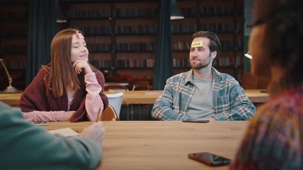 Young People Students Sitting Around Table Playing Funny Guessing Game