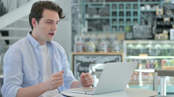 Successful Young Man Celebrating on Laptop in Cafe