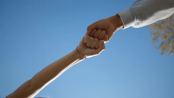 Bottom View of Friends Fist Bumping Greeting Each Other Over Blue Background