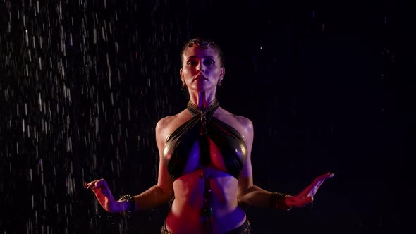Female Dancer with Big Breasts is Dancing Exotic Oriental Dance Under Rain at Night