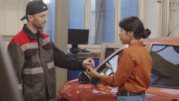Mechanic Giving Car Key to Client in Auto Service Garage