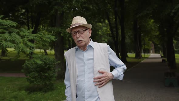 An Old Man Holds His Heart with His Hand Because of Heartache