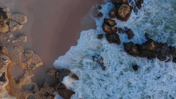 Incredible aerial drone view of waves hitting the rocky beach shoreline