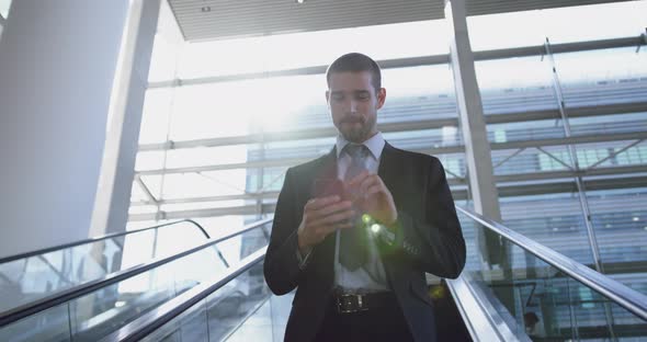 Businessman using mobile phone on escalator in a modern office 4k