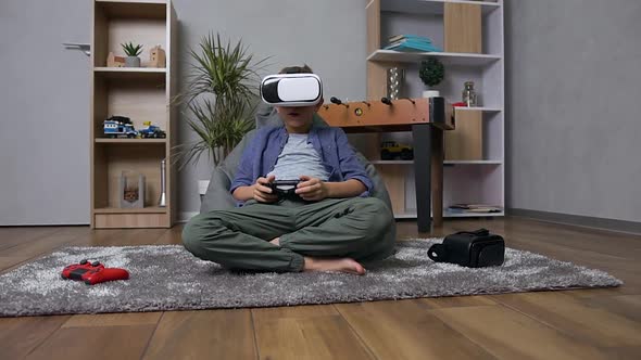 Boy Sitting on Inflatable Armchair Playing Video Game USing Gamepad