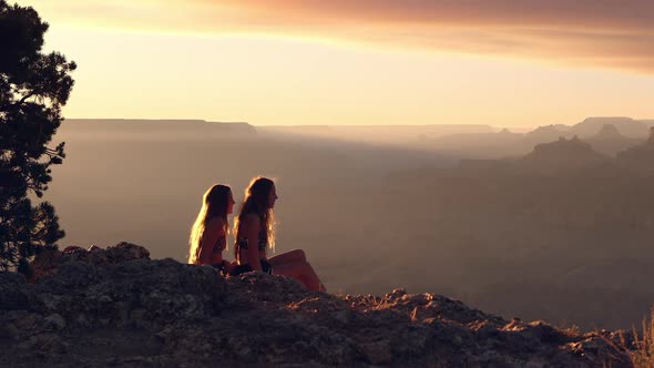 Women enjoying sunset view and offering help to other as she stands