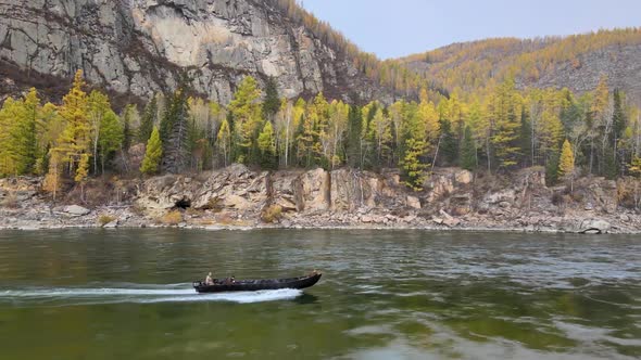 a Motor Boat Sails From Left To Right Against the Backdrop of Huge Mountains