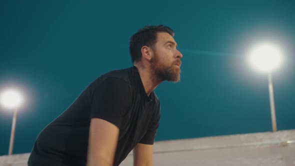 Low angle shot of concentrate beard man dribbling with basketball outdoors in the evening