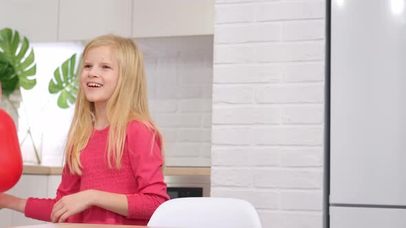 Little Blonde Girl Dancing with Red Heart Shape Balloons at Home