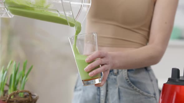 Unrecognizable Slim Young Caucasian Woman Pouring Green Healthy Vegetarian Drink in Glass From