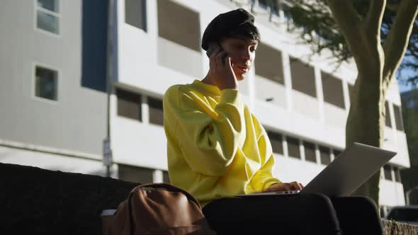 Transgender adult using phone and laptop in the street