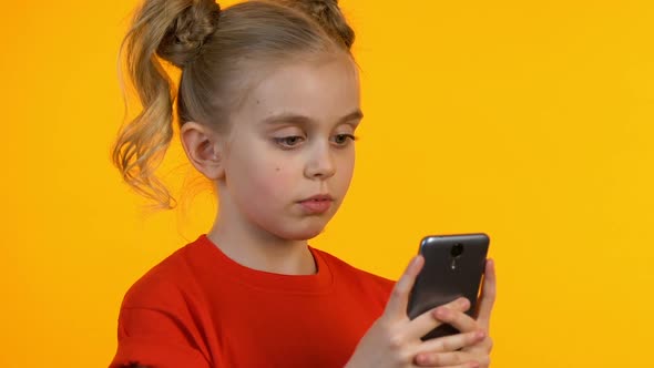 Glad Female Kid Scrolling on Cellphone, Testing New Application, Sales or Games