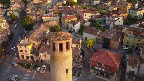 Drone view of a historical tower in a small village during a sunset. italy