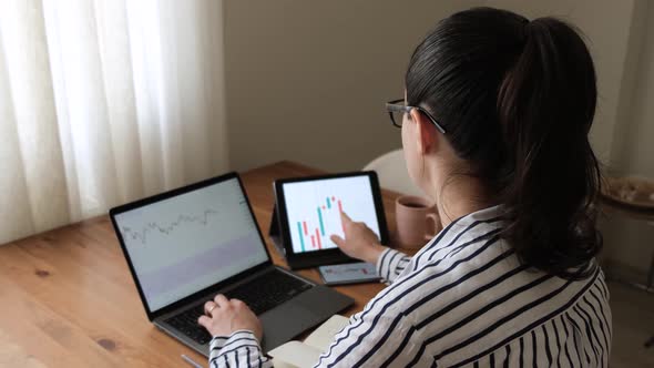 business woman following charts with laptop at home. Stockbroker young woman working at home.
