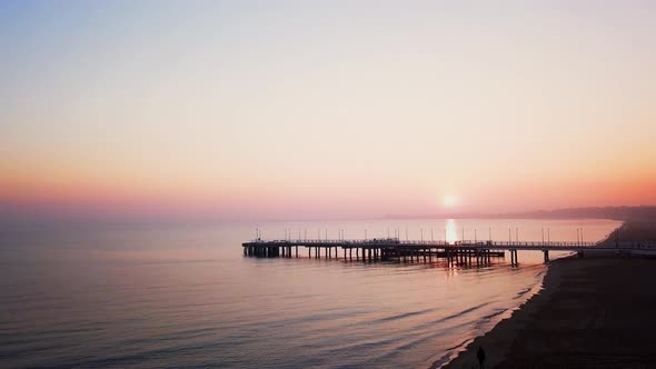 Foggy sunrise over the sea. Hazy morning. Orange sun. Drone footage. Rise over the pier. Baltic Sea,