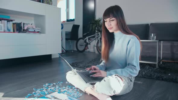 Young woman sitting cross legged at home typing on laptop smart device sitting cross legged in her m