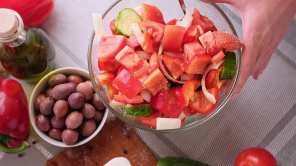 Greek Salad Preparation Series Concept  Woman Mixing Chopped Vegetables in a Glass Bowl