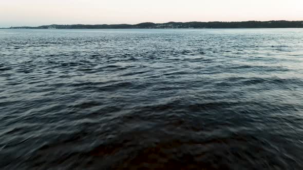 Drone flying close to the ocean surface with the coast of Stavern City in the background