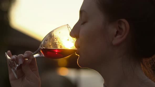 Close Up Of Young Woman Winemaker Drinking Red Wine In Vineyard At Sunset