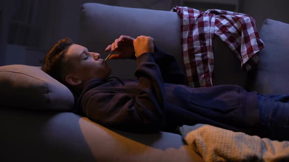 Teenager Stretching on Sofa and Lighting Cigarette, Carefree Behavior, Addiction