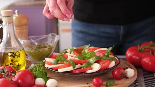 Salting Caprese Salad  Mozzarella Cheese Balls Sliced Cherry Tomatoes and Basil