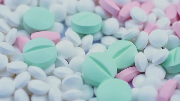 Round Green and Pink Medicines Lie with White Antiviral Pills. Rotation