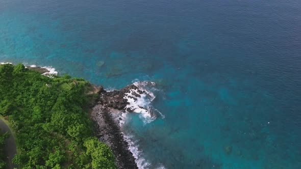 Aerial: Cliffside Full of Greenery and Blue Sea with Vast of Corals Underneath.