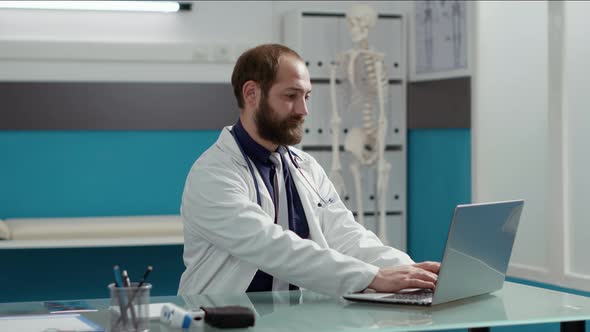 Portrait of General Practitioner Working on Laptop to Plan Checkup Visit