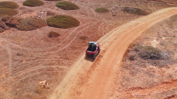 Tracking shot following a four wheeler racing through dessert dirt paths