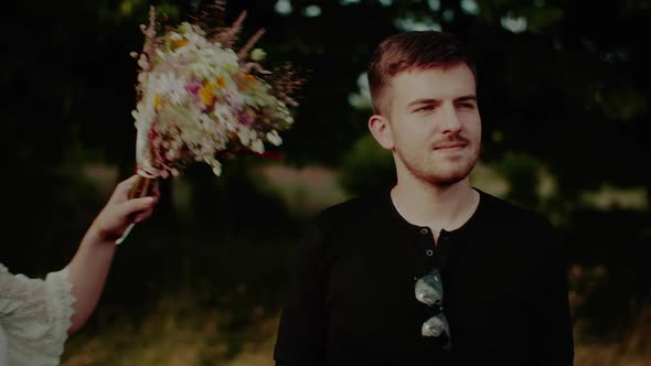 Girl Hugs Her Lover Holding a Bouquet of Wildflowers