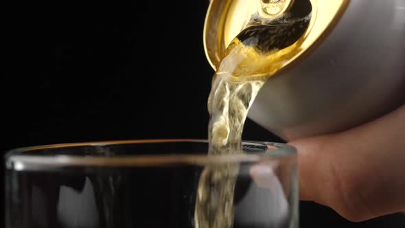 Pouring Cold Beer into a glass with water drops. Can of Beer close up.