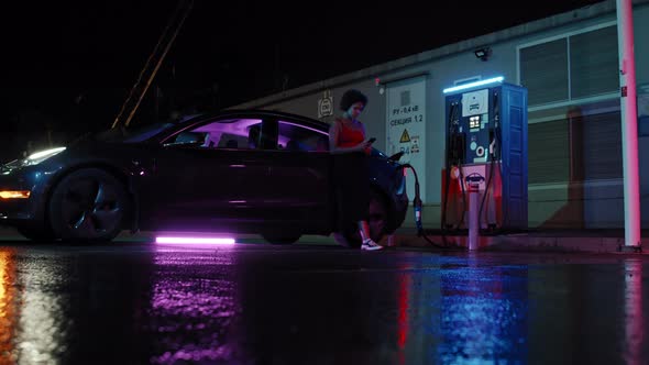 African-American Woman Waiting at EV Station