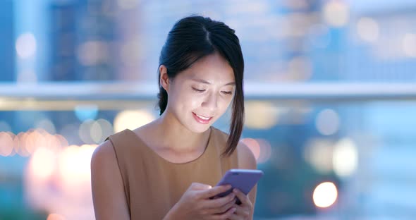 Asian woman check on cellphone in city at night