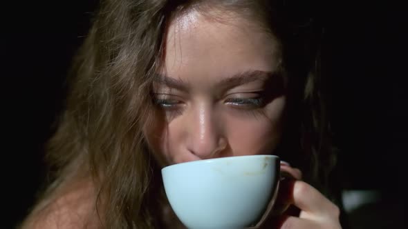 Close-up of girl drinking coffee with pleasure from a white cup