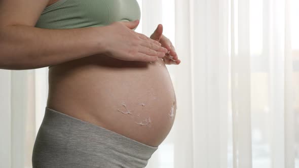 Woman Applies Rubbing Moisturizing Cream on Pregnant Belly