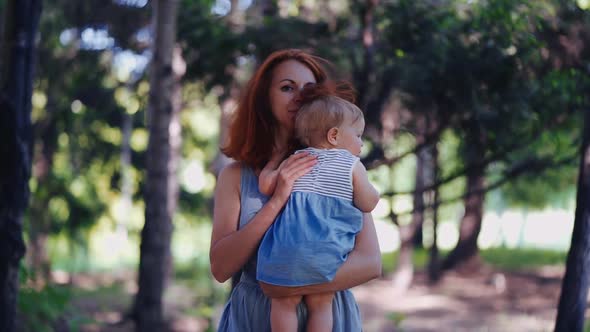 mom holds the baby in her arms walking in the forest or in the park