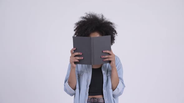 Young Beautiful African Woman with Eyeglasses Covering Face with Book
