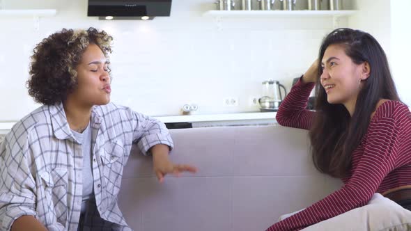 Two Girlfriends Gossiping While Sitting on the Couch