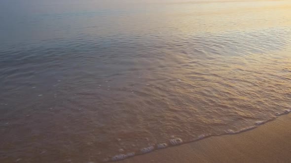 Calm Sea Shore with Crushing Waves on Sandy Beach at Sunrise