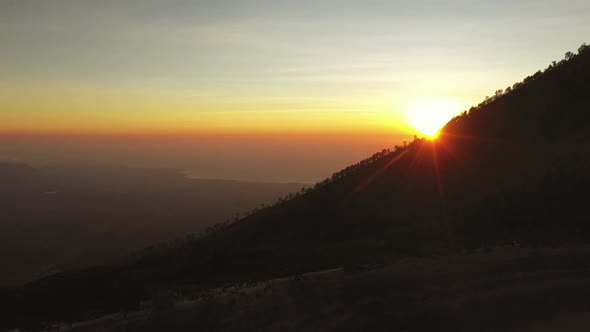 Aerial view clip of a beautiful sunrise slowly reveal from behind a mountain