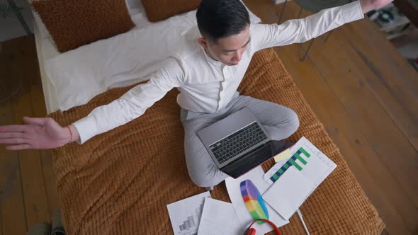 Top View of Chinese Male Business Analyst Putting Hands Together Meditating in Home Office in