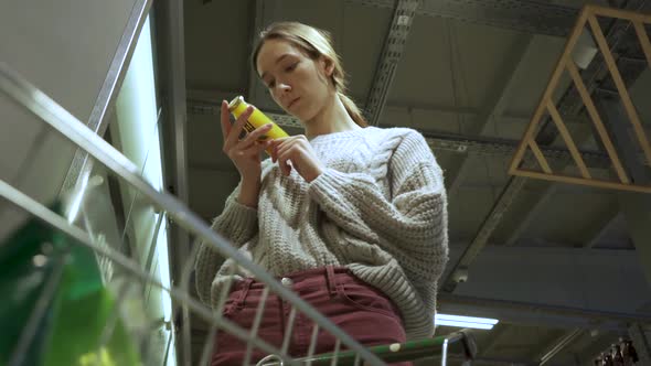 A Young Female Customer Reads the Composition of the Drink on the Juice Bottle