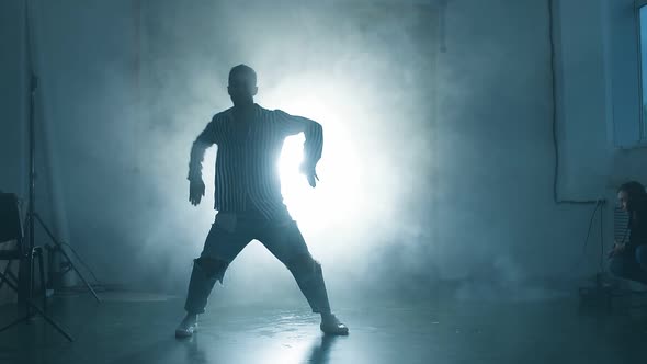 Silhouette of Young Man Performing Hip Hop Moves on Stage with Spotlight in Background
