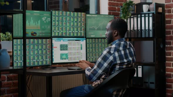 Male Broker Using Forex Trade Exchange Statistics on Multiple Monitors