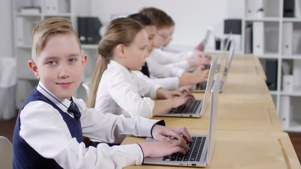 10-Year-Old Caucasian Boy Using Laptop in Class and Posing for Camera