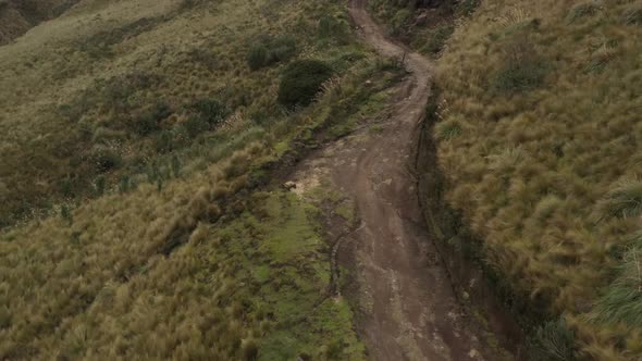 Bird eye view that slowly approaches a dirt road high up in the andean mountains